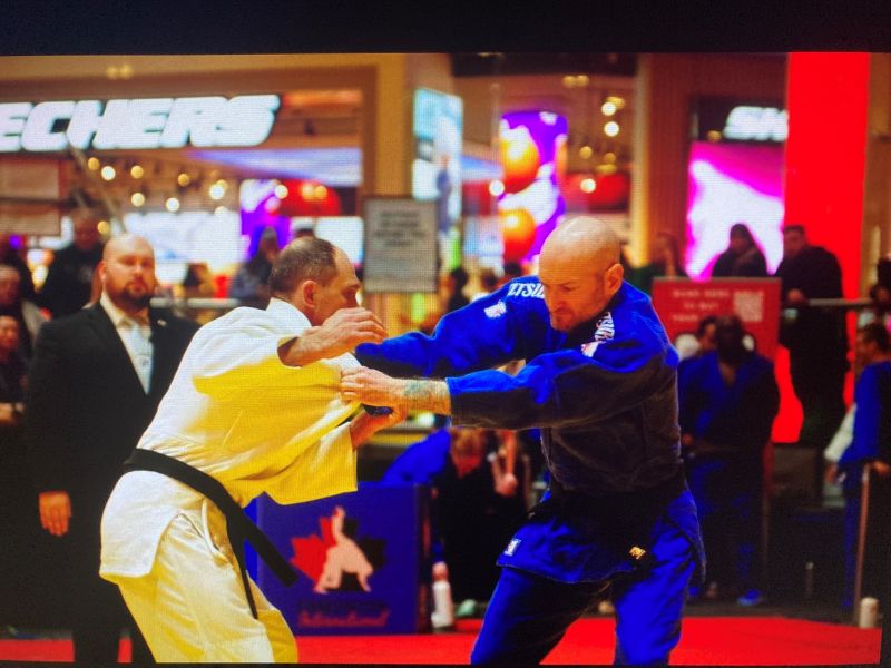 Two judo players in white and blue gi gripping each others lapels.