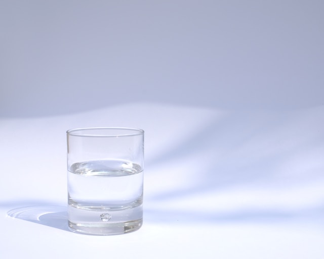 a glass of water on a white background with refracting light.