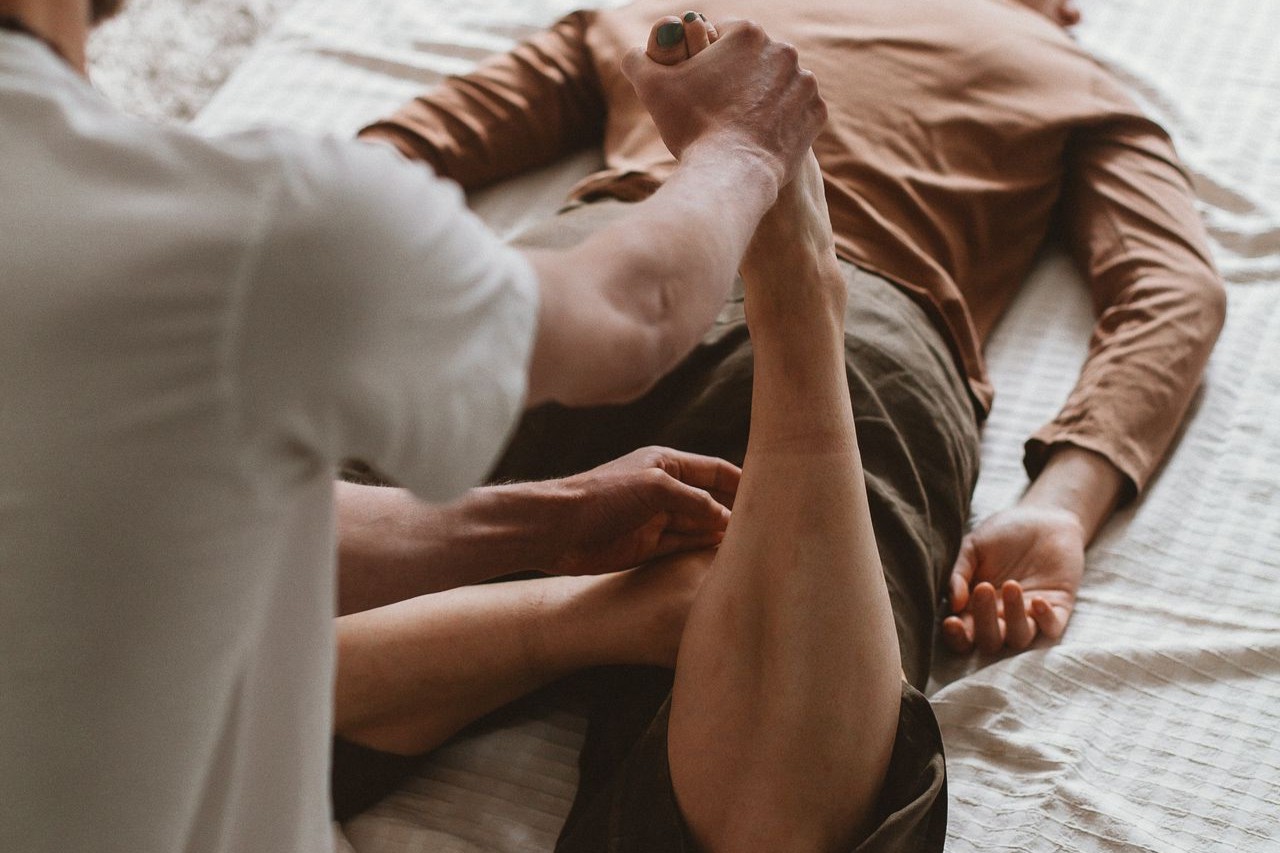 Bodywork Therapist helps client stretch during a session indoors.